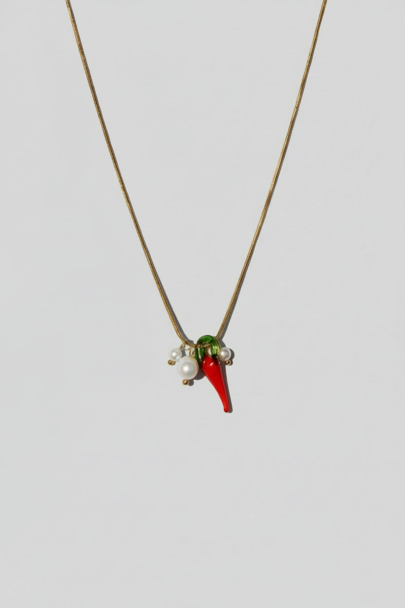Necklace with red and green pendant on a beige background