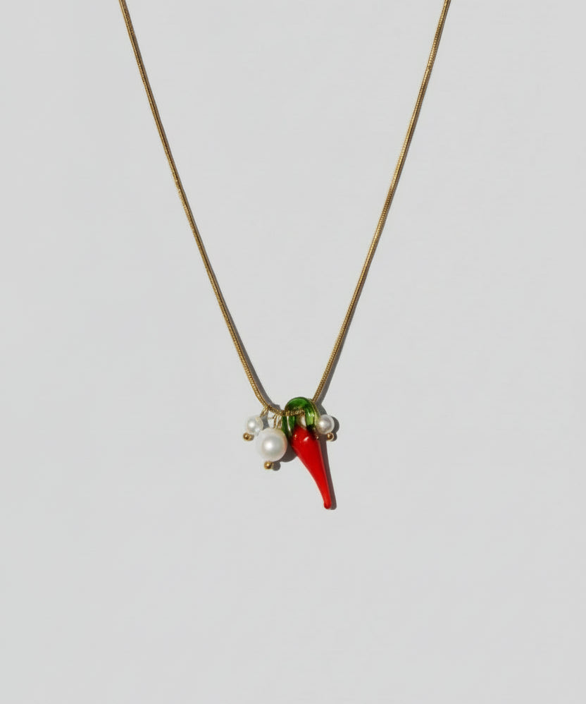 Necklace with red and green pendant on a beige background
