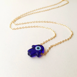 Gold necklace with a blue evil eye pendant on a white background